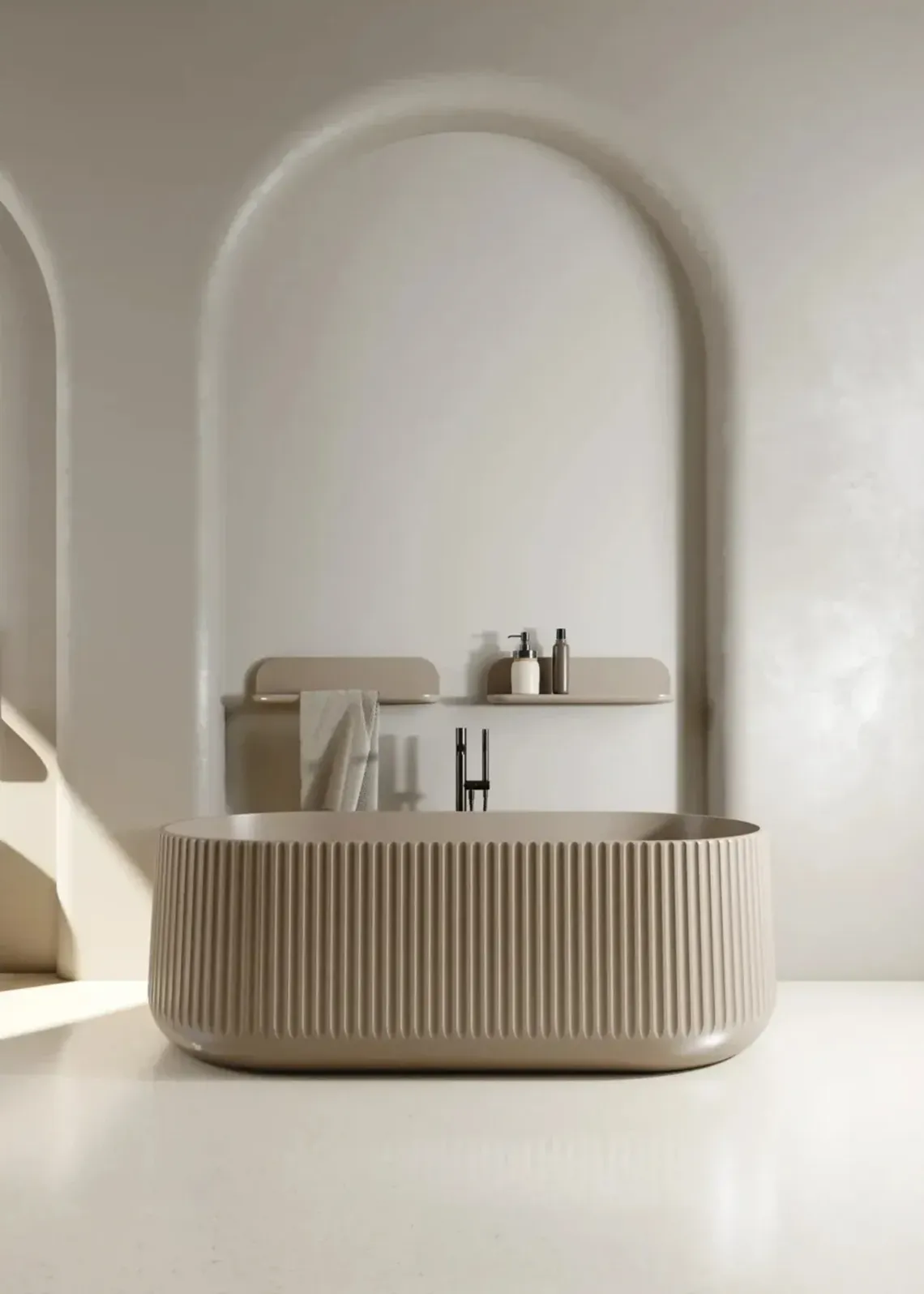 Vasca beige scanalata con forme arrotondate, inserita in un bagno dai toni caldi con pareti ad arco e mensole minimal.