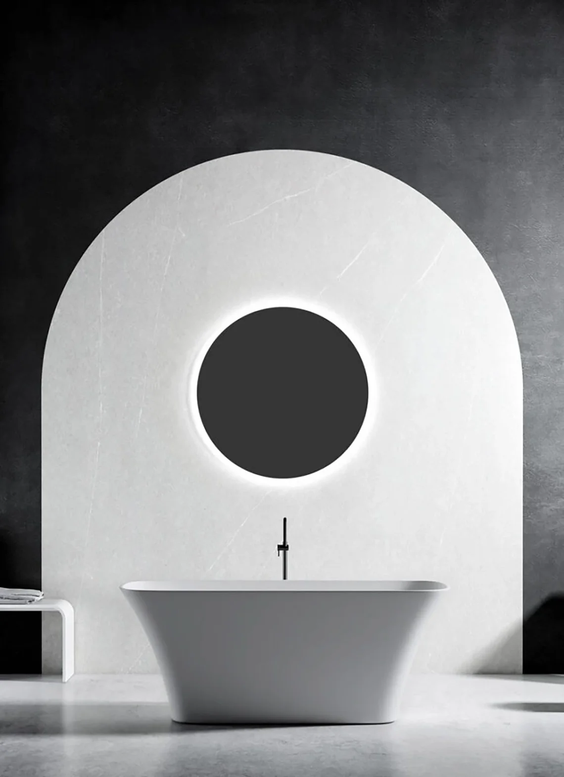 Vasca bianca freestanding davanti a parete con arco bianco e specchio tondo retroilluminato, in bagno dal design moderno in bianco e nero.