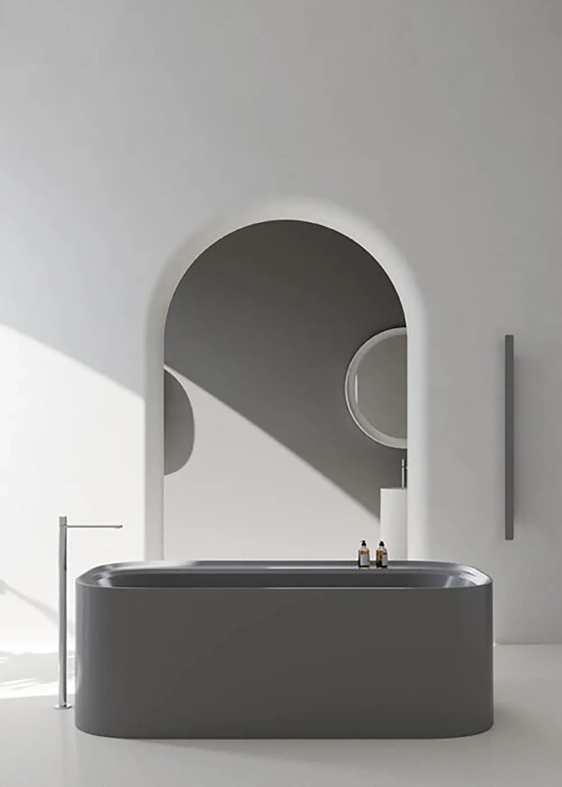Vasca freestanding grigia opaca in bagno moderno con parete bianca ad arco e rubinetteria minimal