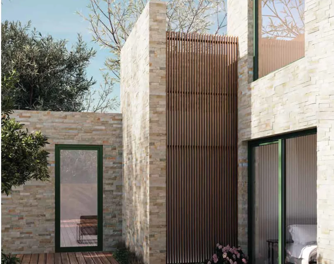Facciata in pietra con infissi in alluminio verde e terrazzo in legno