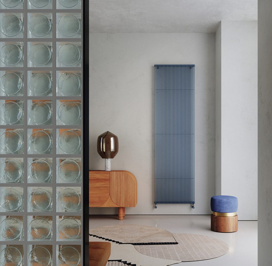 Radiatore verticale blu in ambiente living moderno con arredi in legno curvo e pareti neutre.