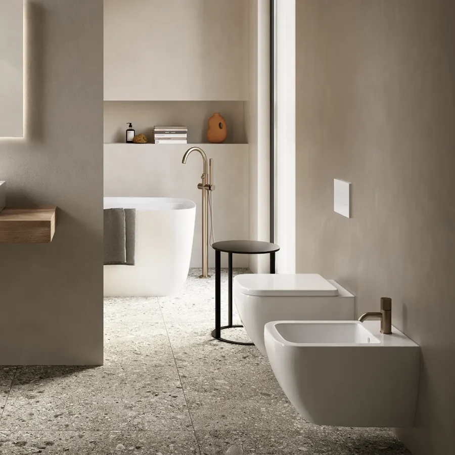Sanitari sospesi Hatria con rubinetteria in ottone e pavimento effetto pietra in bagno moderno.
