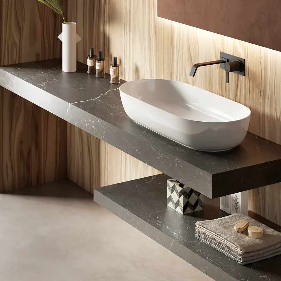 Lavabo da appoggio bianco su mensola sospesa in pietra scura, con rubinetteria nera e parete in legno naturale.