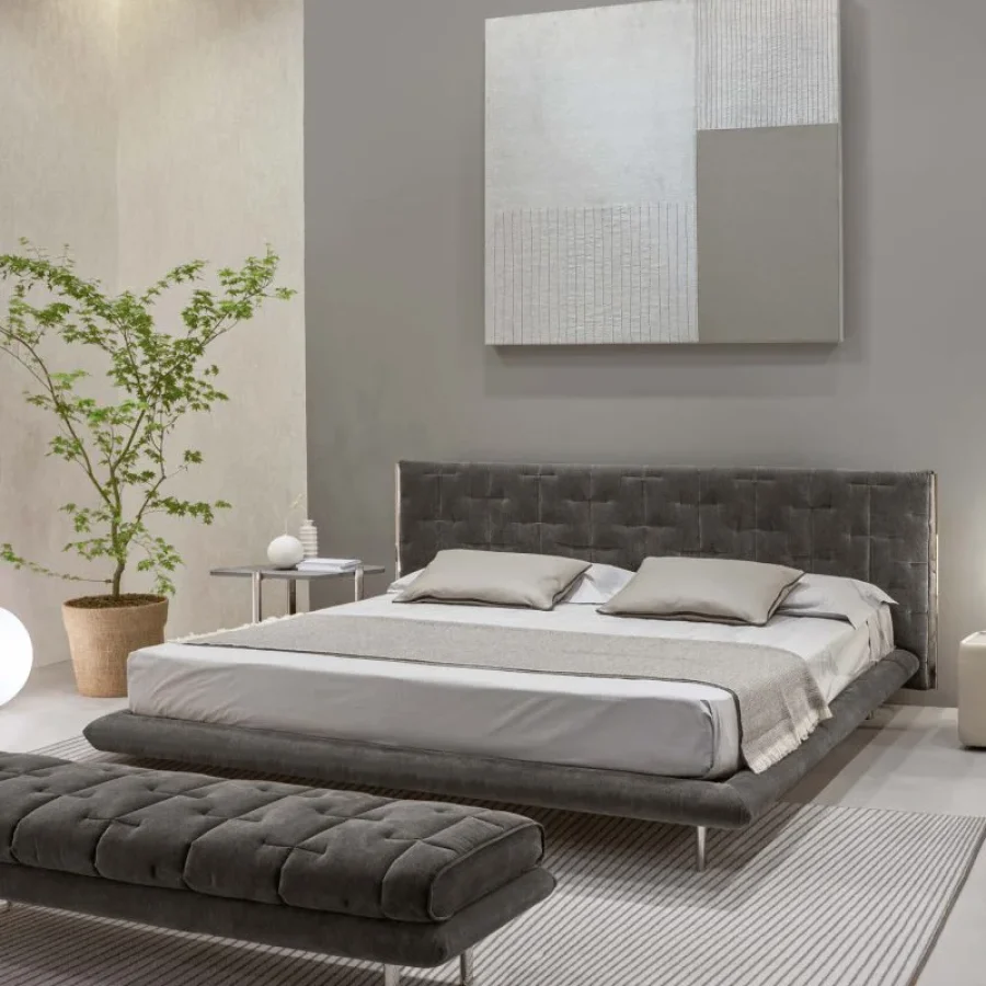 Letto con testiera avvolgente rivestita in pelle marrone e cuscini decorativi tono su tono