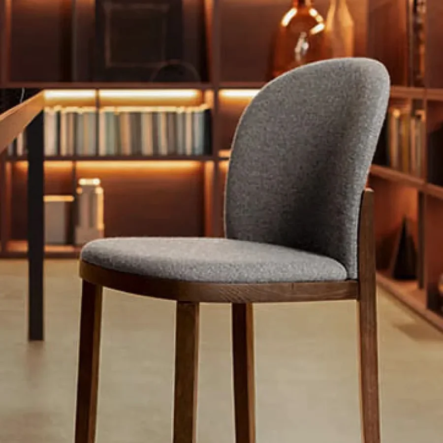 Sedia imbottita Pianca Orchestra con rivestimento grigio e gambe in legno scuro.