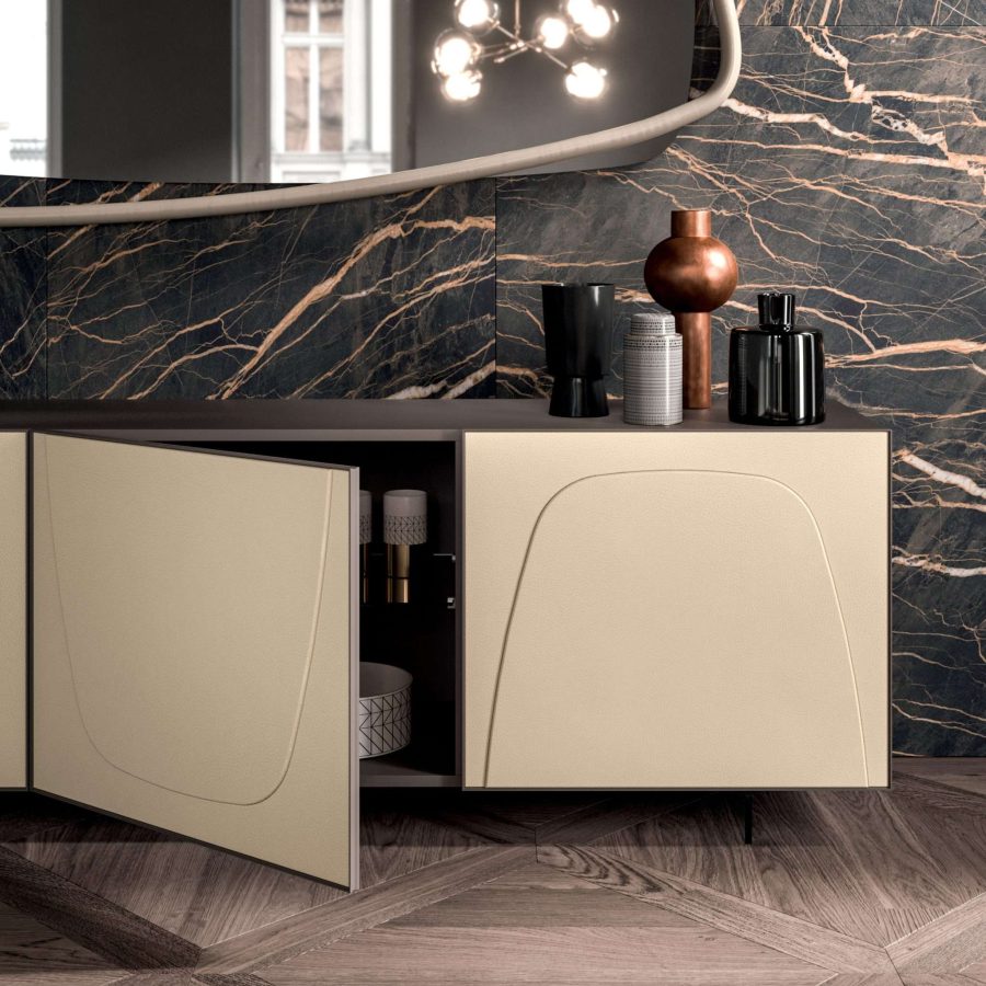 Madia beige con ante bombate e parete marmorizzata scura.