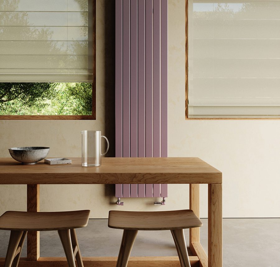 Radiatore verticale lilla in zona pranzo con tavolo e sedie in legno chiaro e pareti beige.