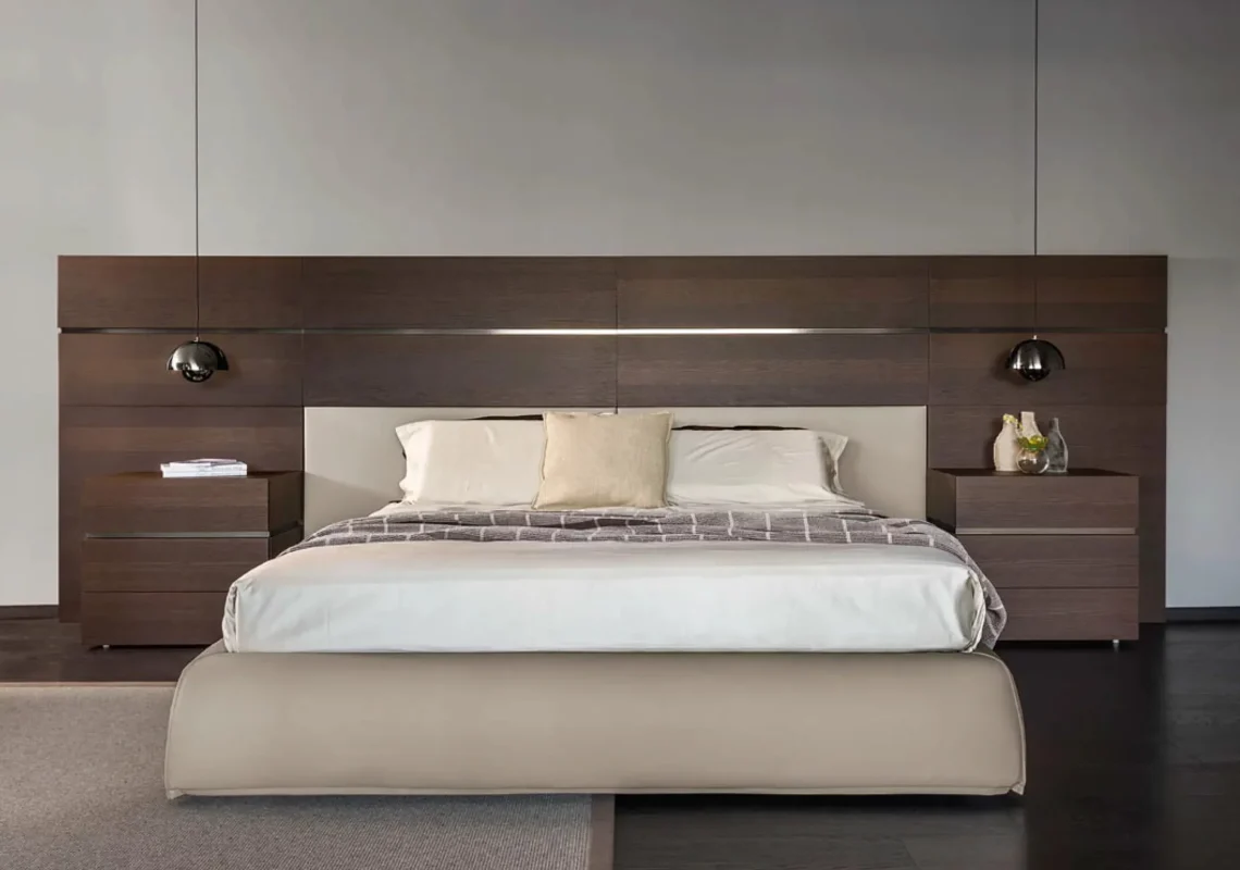 Letto matrimoniale con testiera integrata in una grande boiserie in legno scuro