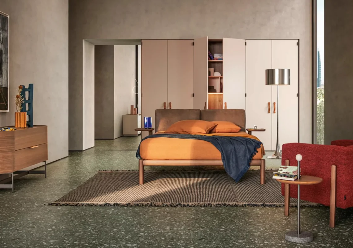 Letto con struttura in legno chiaro e testiera imbottita marrone, in camera dai colori caldi