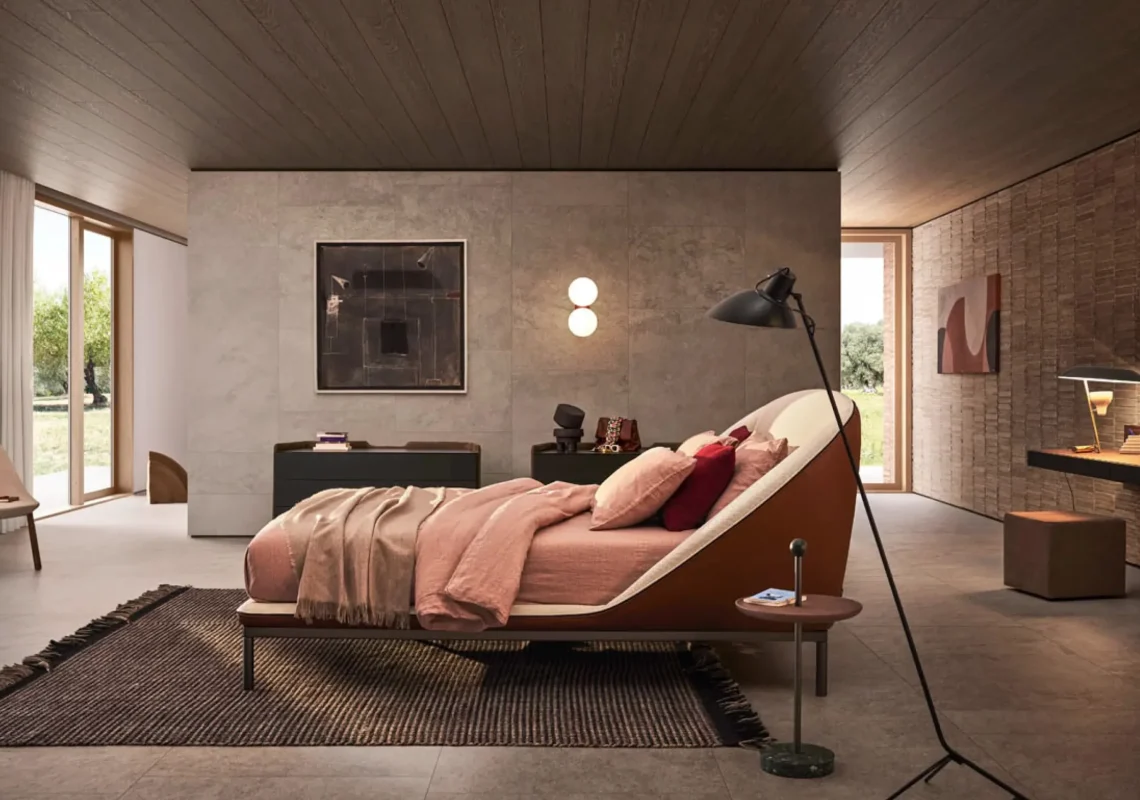 Letto con struttura curvata in tessuto beige e copertura rosa, in camera materica e intima.