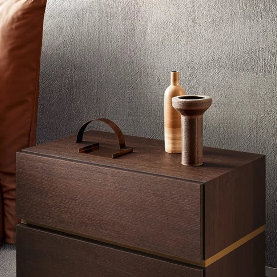 Comodino rettangolare in legno scuro con due cassetti e oggetti decorativi.