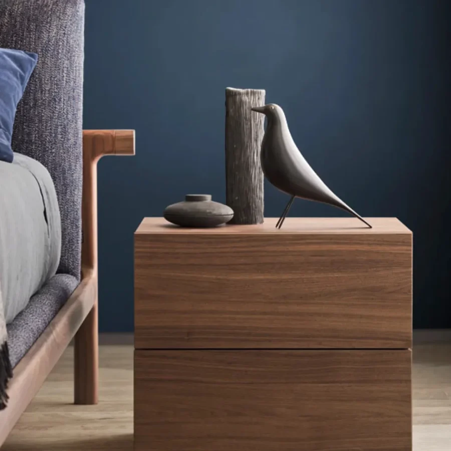 Comodino moderno in legno naturale posizionato accanto a un letto con struttura in legno