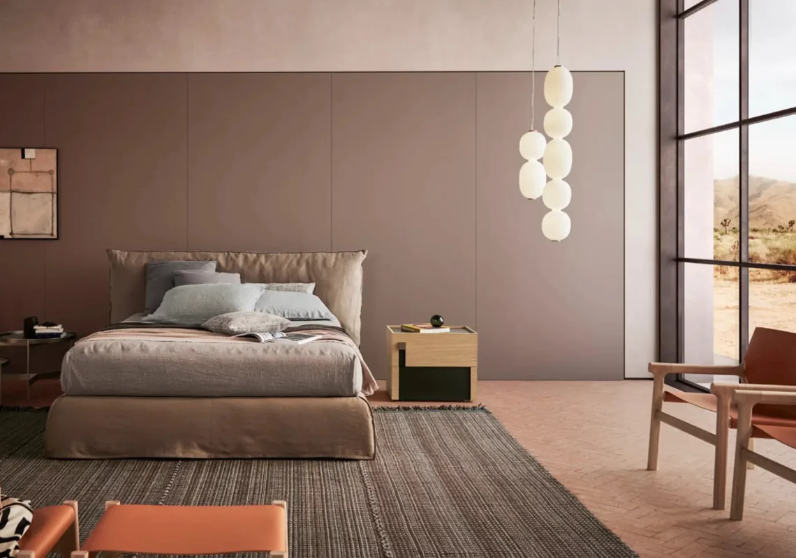 Letto in tessuto tortora con forme morbide e stile contemporaneo.