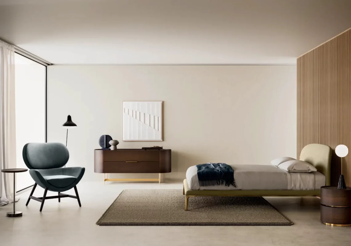 Letto chiaro con testiera curva in una camera con elementi in legno e arredi scultorei.