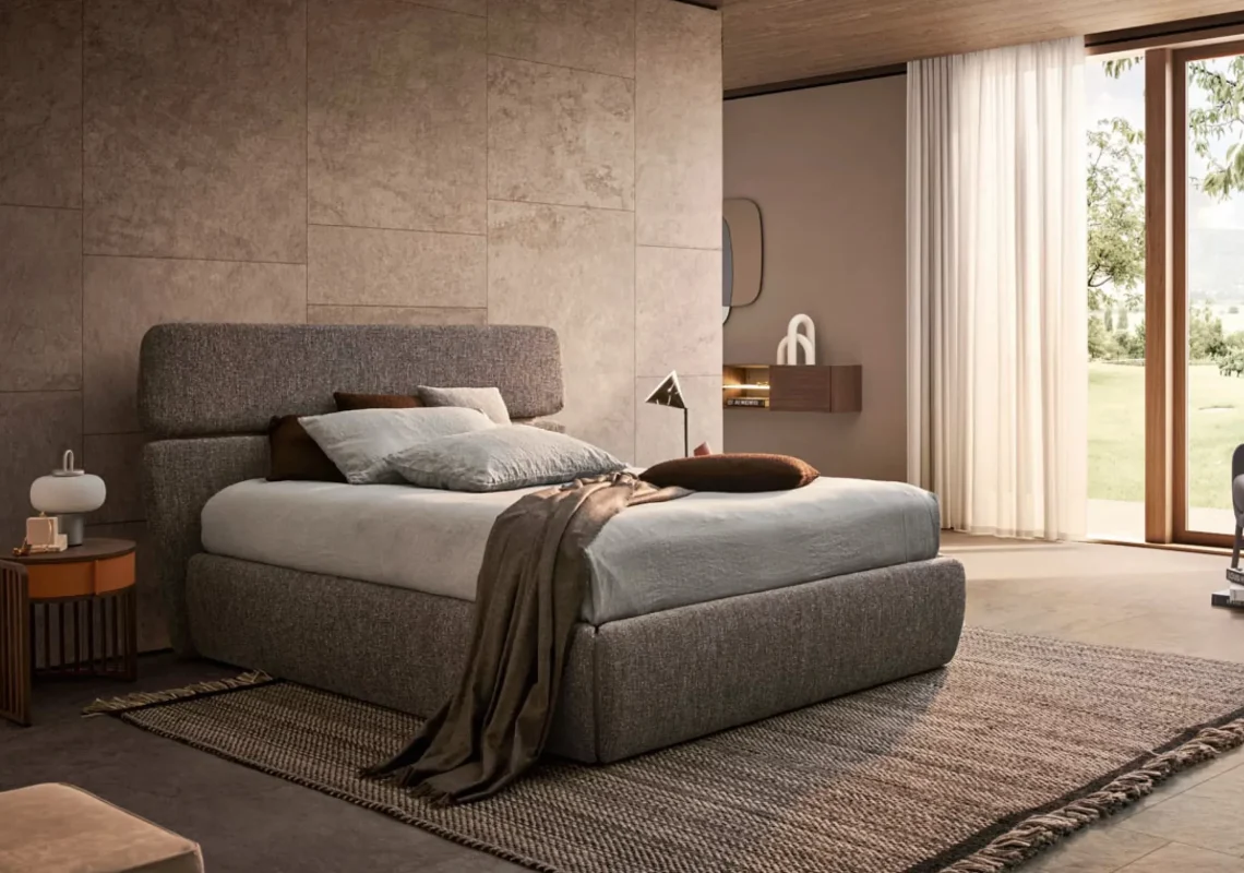 Letto in tessuto grigio antracite con testiera imbottita in una camera moderna con luce naturale