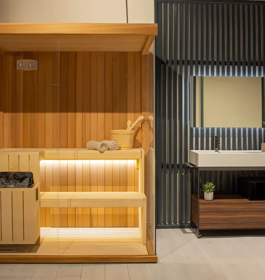 Sauna in legno con panche su due livelli, luci LED e accessori tradizionali, integrata in ambiente bagno dal design moderno.