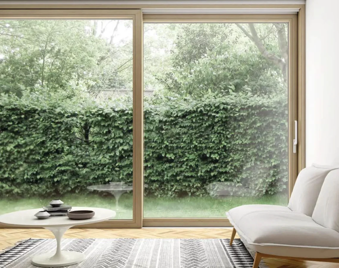 Due sedie moderne con schienale bianco e gambe in legno davanti a una finestra con infisso chiaro in legno naturale.