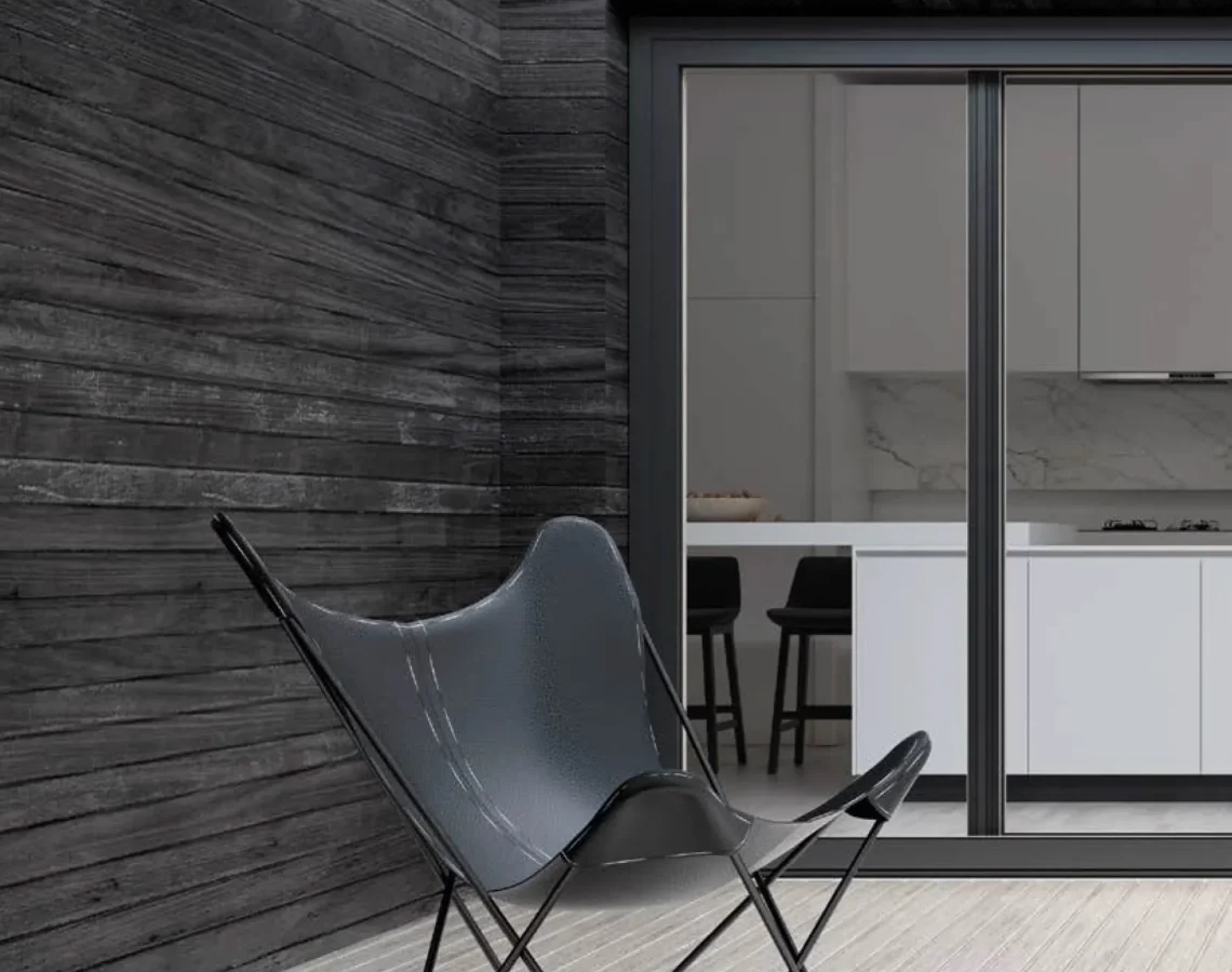 Vista esterna di una cucina moderna con ampie vetrate scorrevoli nere incorniciate da legno scuro.