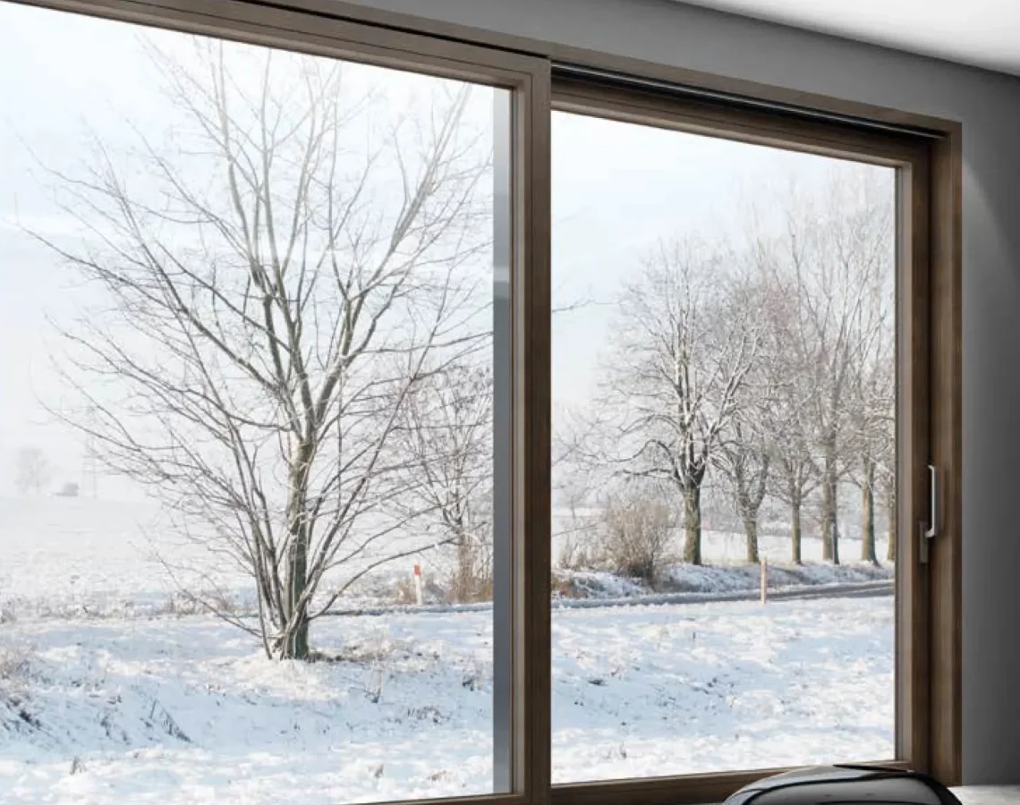 Veranda coperta con vetrata scorrevole in alluminio e arredo in rattan su pavimento in legno