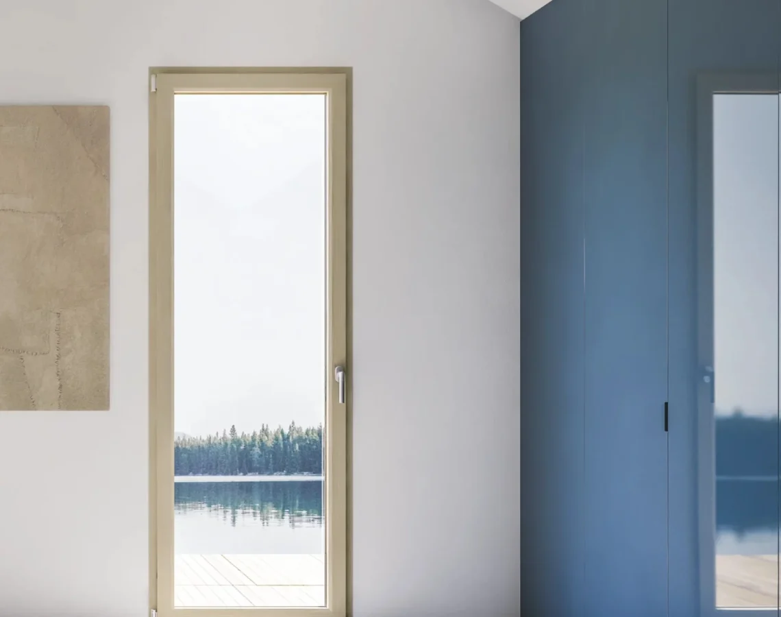 Porta finestra con telaio bianco e divano grigio in soggiorno dallo stile moderno
