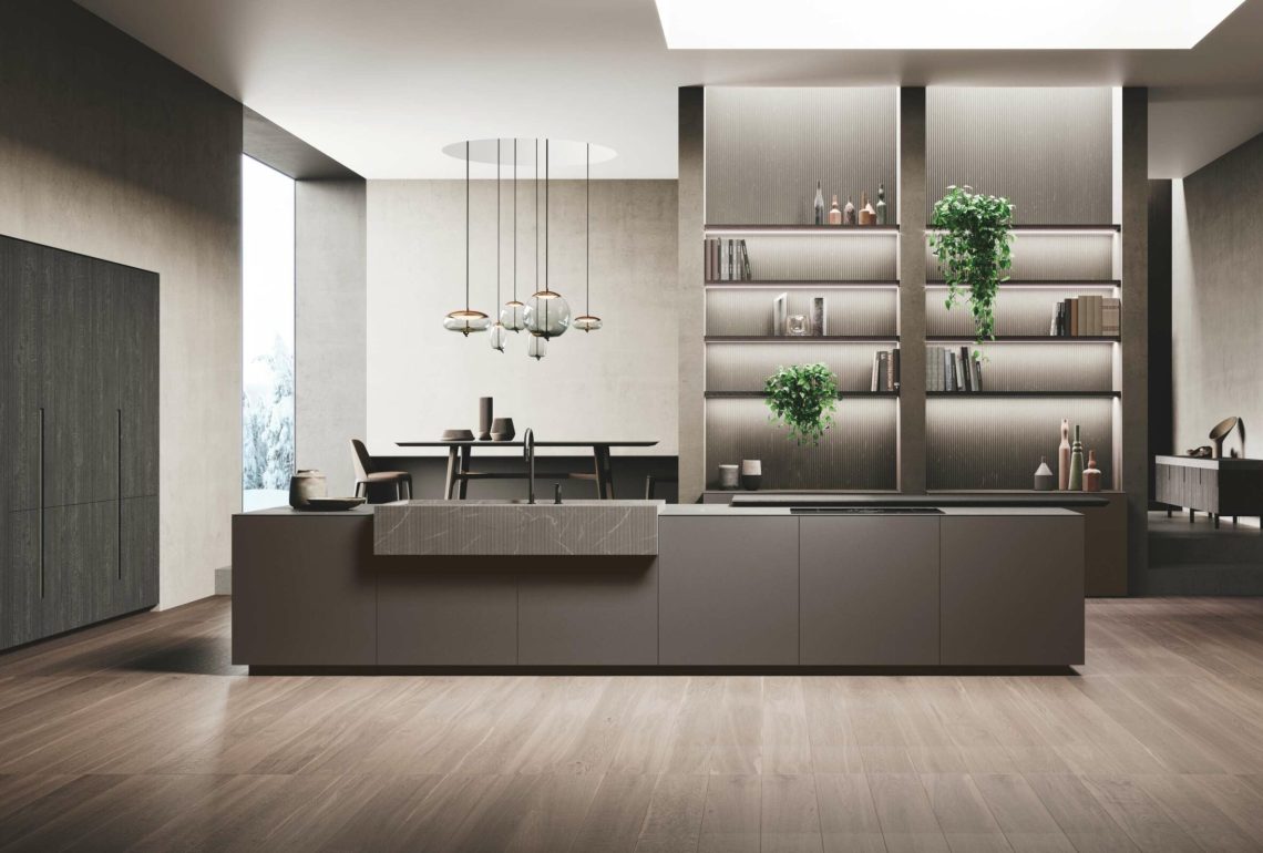 Cucina con isola centrale beige e lavello in pietra, abbinata a parete libreria con mensole retroilluminate e tavolo da pranzo.