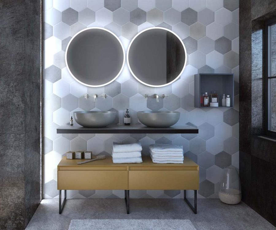 Mobile bagno doppio con lavabi rotondi grigi, specchi retroilluminati e parete decorata con piastrelle esagonali bianche e grigie.