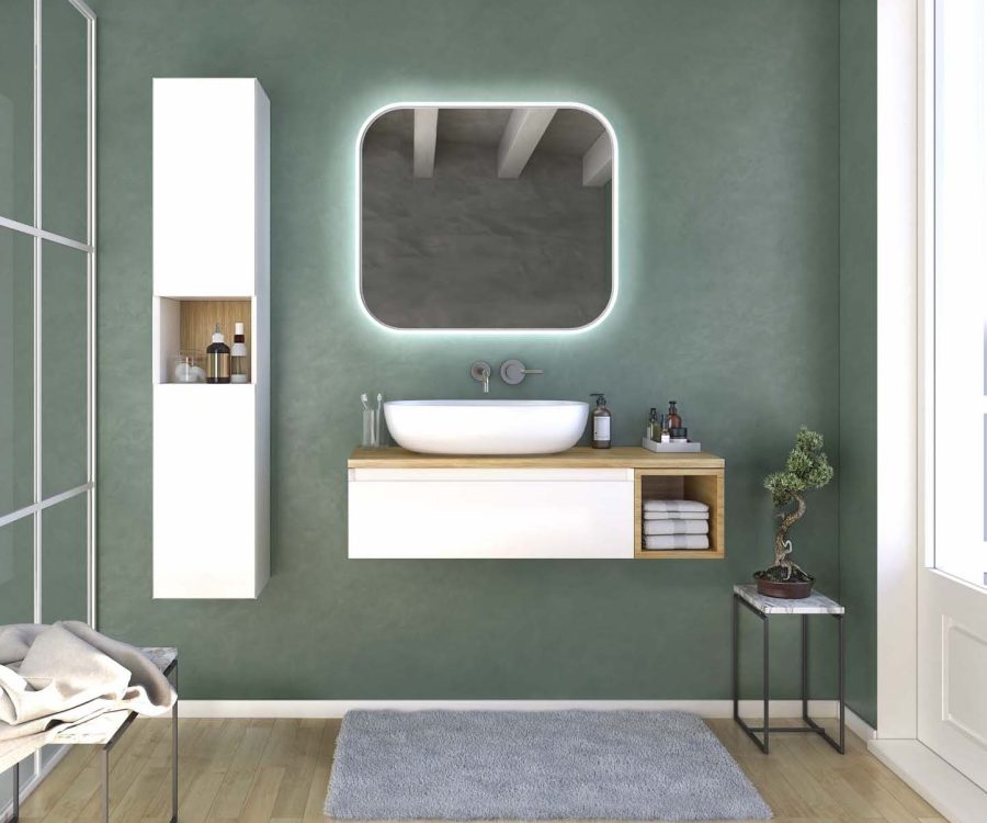 Arredo bagno sospeso bianco con top in legno chiaro, lavabo rotondo, specchio retroilluminato e parete verde salvia.